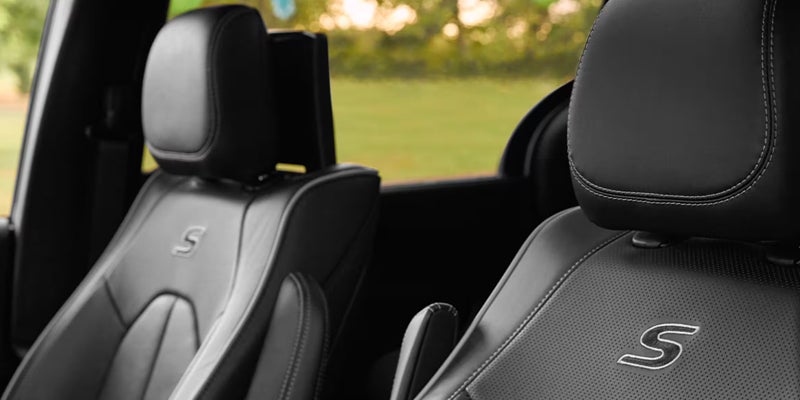 Close-up of black leather car seats with "S" logos embroidered on them, seen from the passenger side.