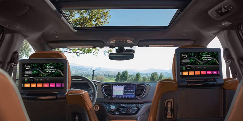 Interior of a car with two Fire TV screens on the back of the front seats, showing "Take your entertainment on the road."