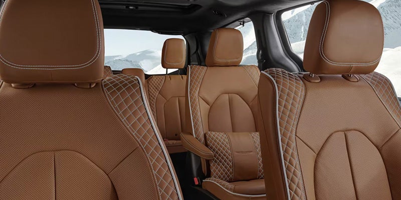 Luxury car interior with tan leather seats featuring diamond stitching, viewed from the driver's side rear.