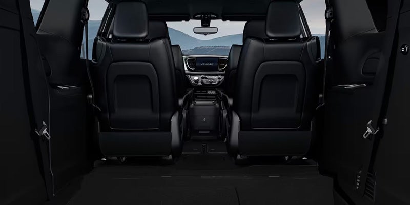 View from the rear of a minivan interior looking forward, showing two black leather second-row seats and the dashboard.