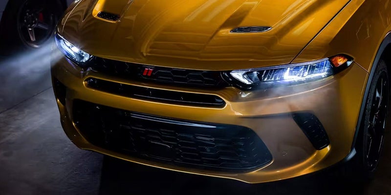 Front view of a shiny gold Dodge R/T with bright headlights, black grille, and subtle hood vents.