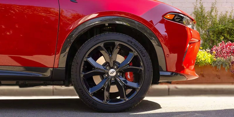 Close-up of a red car's glossy black wheel with a silver hubcap and red brake calipers.