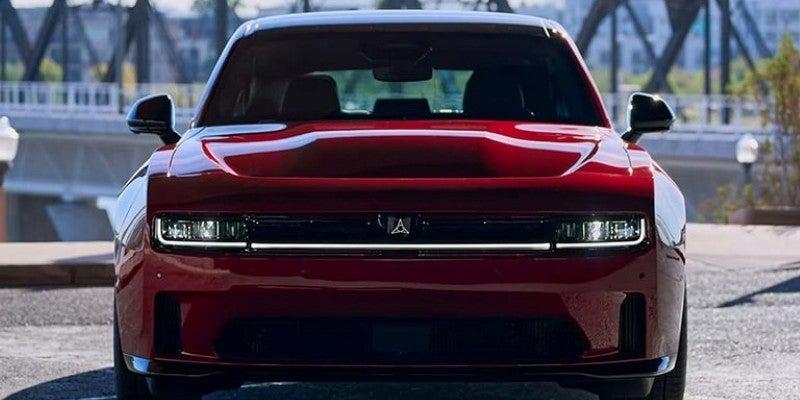Front view of a dark red Dodge Charger Daytona SRT EV concept car with bright horizontal headlights.