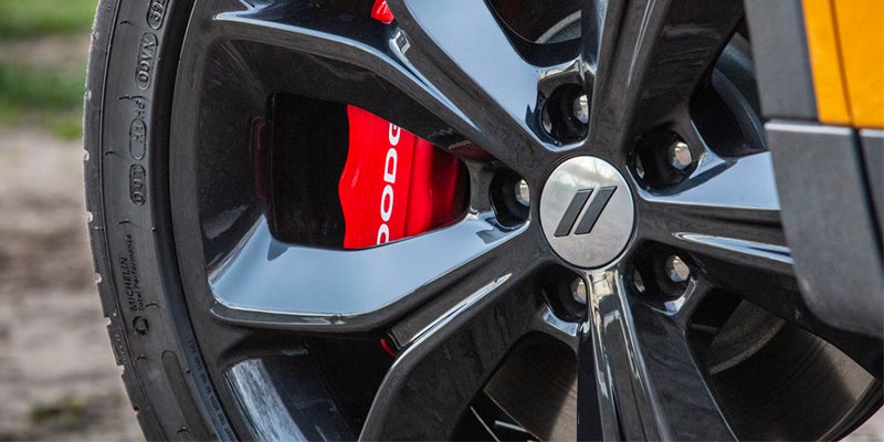 Close-up of a glossy black Dodge Challenger wheel with a red "Dodge" brake caliper.