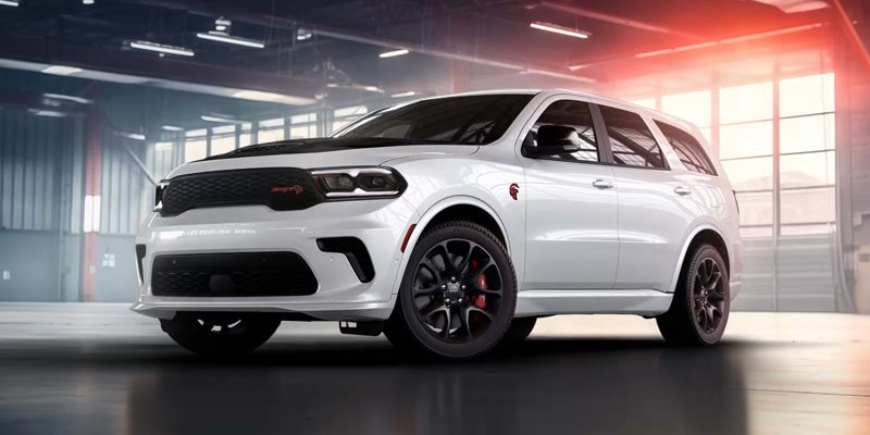 A white Dodge Durango SUV with a black hood scoop and red SRT emblem parked in a garage.