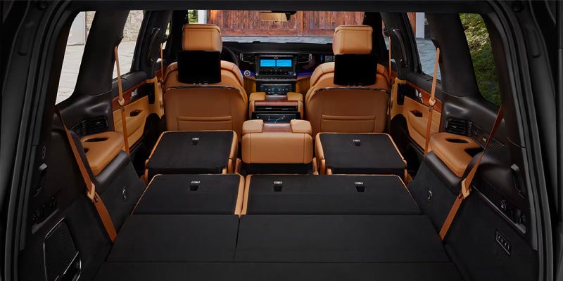 View from the trunk of a luxury SUV, showing extended flat cargo space with folded rear seats revealing tan leather accents.