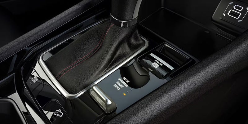 Close-up of a car's center console, showing the gear shift, driving mode selector, and electronic parking brake.
