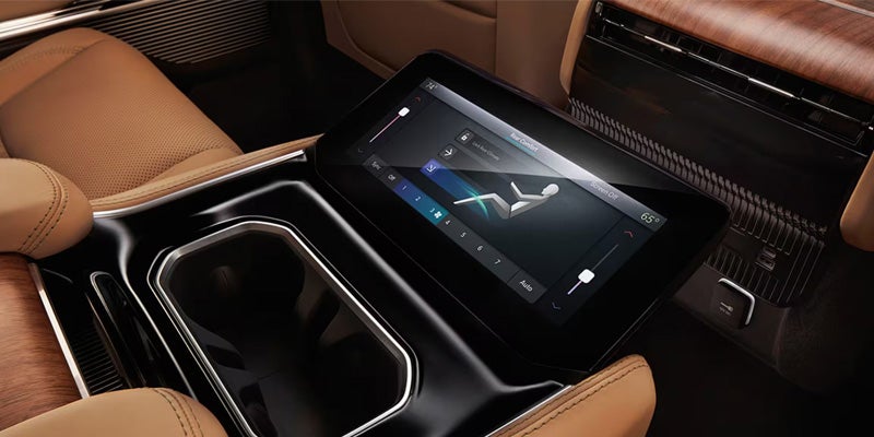 Rear seating area in a car with a center console touch screen showing climate controls for a person lying down.