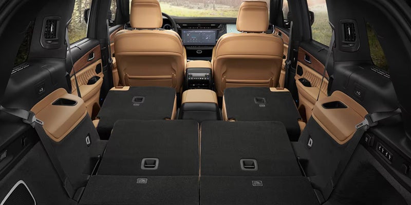 Interior of a car with rear seats folded down, revealing ample cargo space and tan-colored upholstery details.