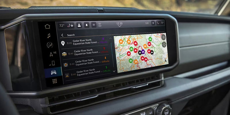 Car infotainment system displaying a map with marked trails and a search menu listing Cedar River North Equestrian State Forest.