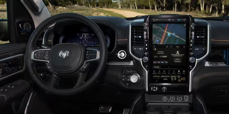 Interior of a dark car showing the steering wheel with controls and a large vertical touchscreen display.
