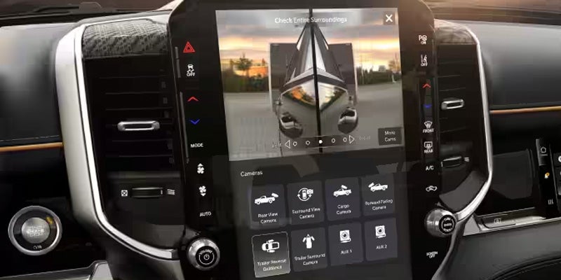 A truck's central touchscreen displaying a camera view of a boat being towed, with camera options below.