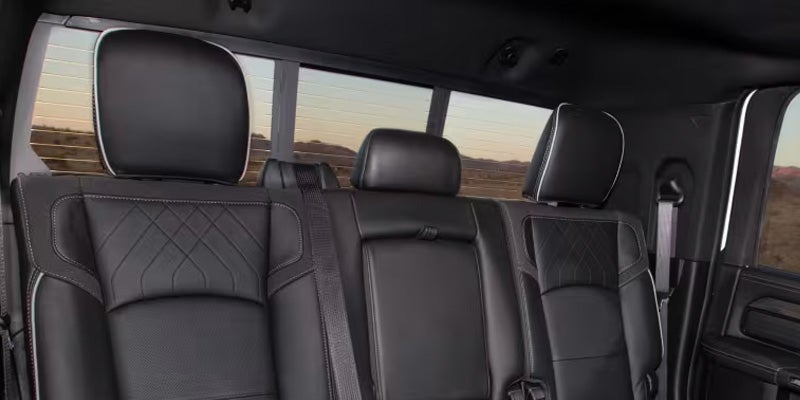 Back seats of a black truck with diamond-stitched leather upholstery, white piping, and headrests.
