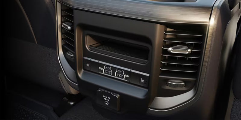 Rear console with dual USB-A and USB-C ports, a 115V AC outlet, two heated seat buttons, and air vents.
