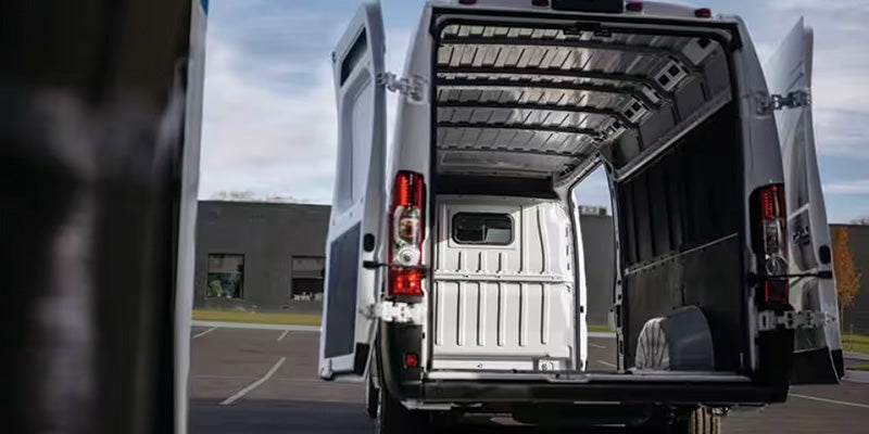 Rear view of a white cargo van with its back doors open, revealing a spacious, empty cargo area.