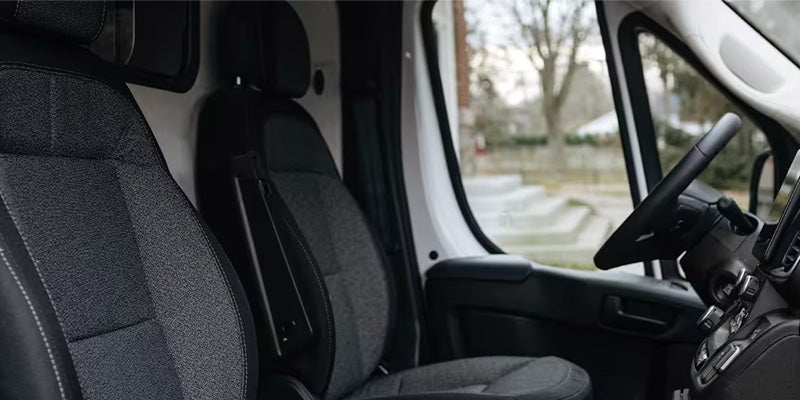 Interior view of a white van, showing the passenger seat in the foreground, and the steering wheel and dashboard on the right.