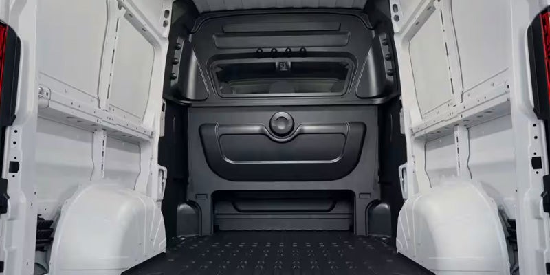 Interior view of an empty white cargo van with a black plastic bulkhead and textured floor.